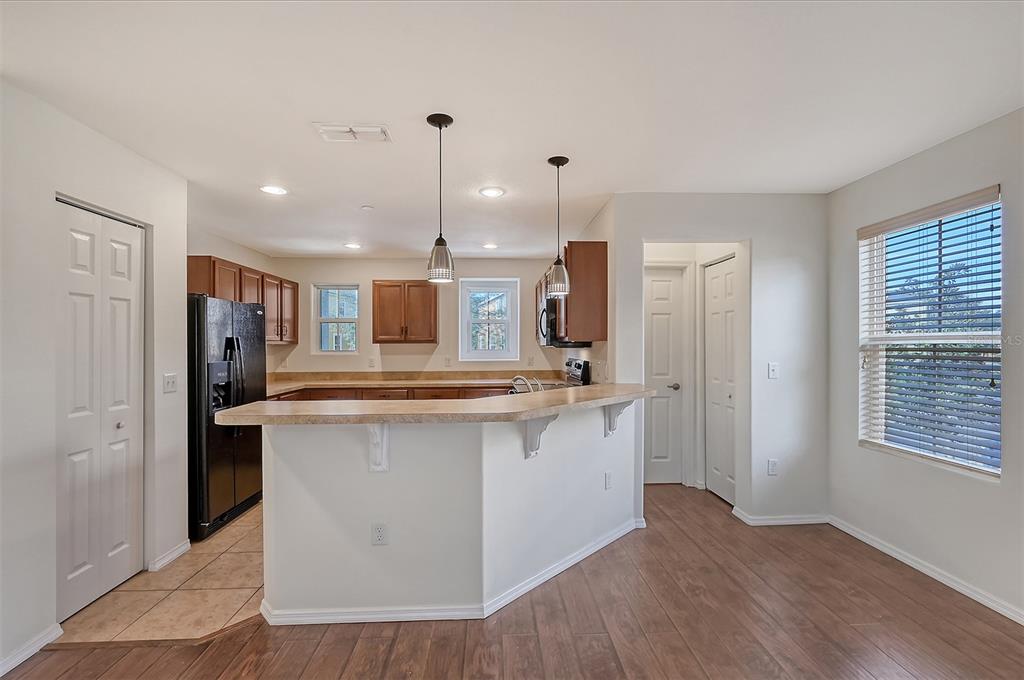8922 White Sage Loop Lakewood Ranch, FL 34202 - Photo 12 of 65 a kitchen with stainless steel appliances granite countertop a refrigerator a sink dishwasher a stove and a dining table with wooden floor
