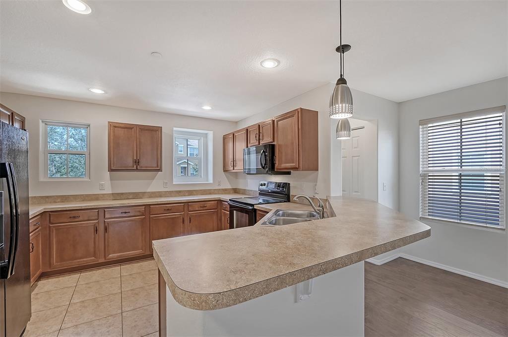 8922 White Sage Loop Lakewood Ranch, FL 34202 - Photo 15 of 65 a kitchen with stainless steel appliances granite countertop a sink dishwasher a refrigerator and a stove with wooden floor