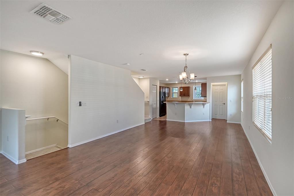 8922 White Sage Loop Lakewood Ranch, FL 34202 - Photo 7 of 65 an empty room with wooden floor kitchen view and windows