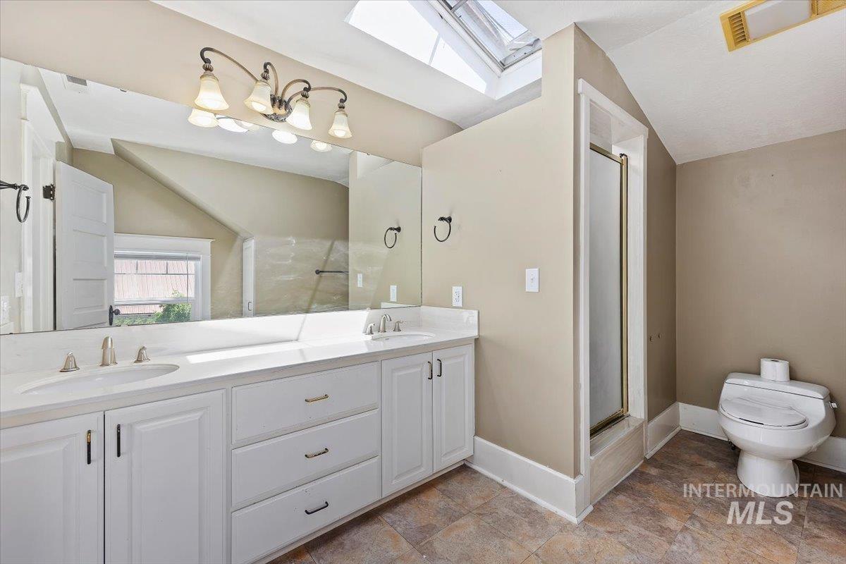 813 7th Street Rupert, ID 83350 - Photo 33 of 48 Bathroom featuring a dual vanity with white cabinetry, a large frameless mirror, and a skylight