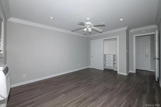 an empty room with wooden floor and ceiling fan