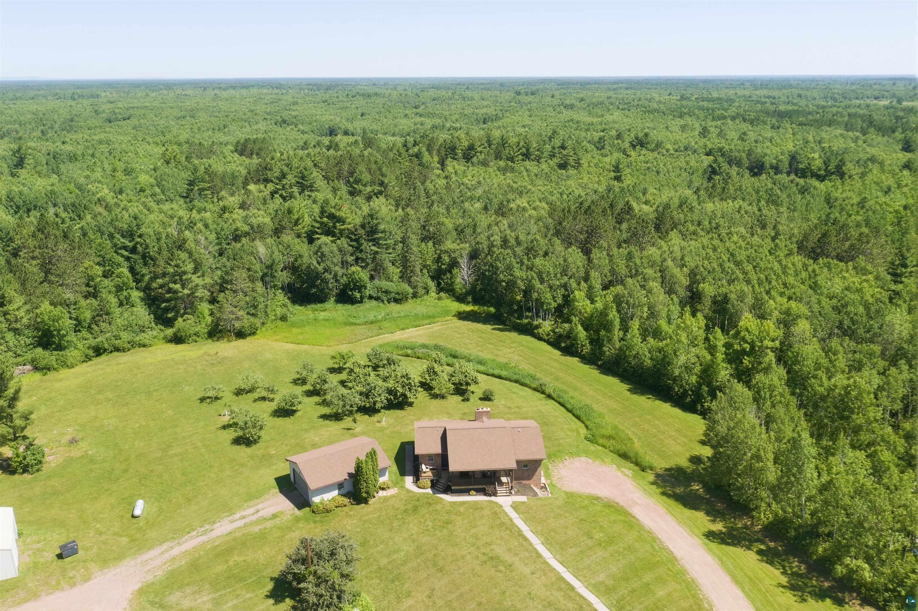 64260 Jolma Road Ashland, WI 54806 - Photo 32 of 35 Expansive woodland property featuring a central residence, detached outbuilding, mature trees, and a gravel driveway