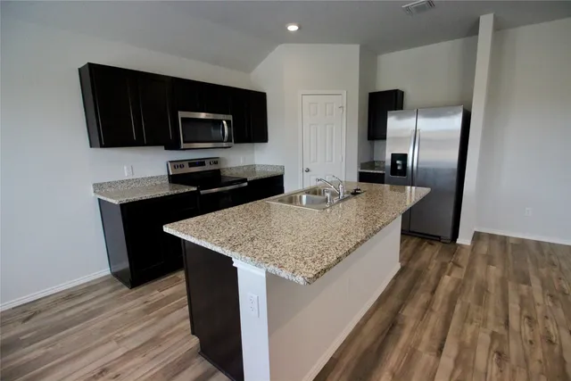 a view of kitchen with kitchen island a sink wooden floor and a counter top space