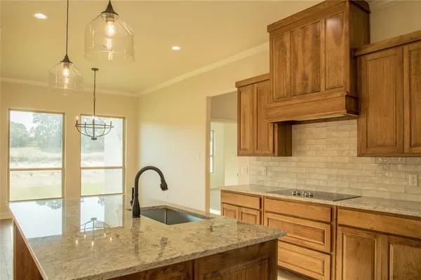 a kitchen with kitchen island a counter top a stove a sink and living area view