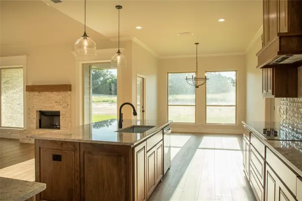 a kitchen with stainless steel appliances granite countertop a sink a stove and a wooden floor