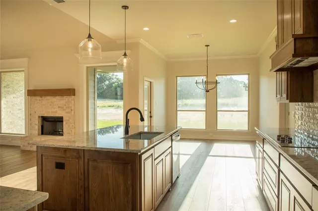 a kitchen with stainless steel appliances granite countertop a sink a stove and a wooden floor