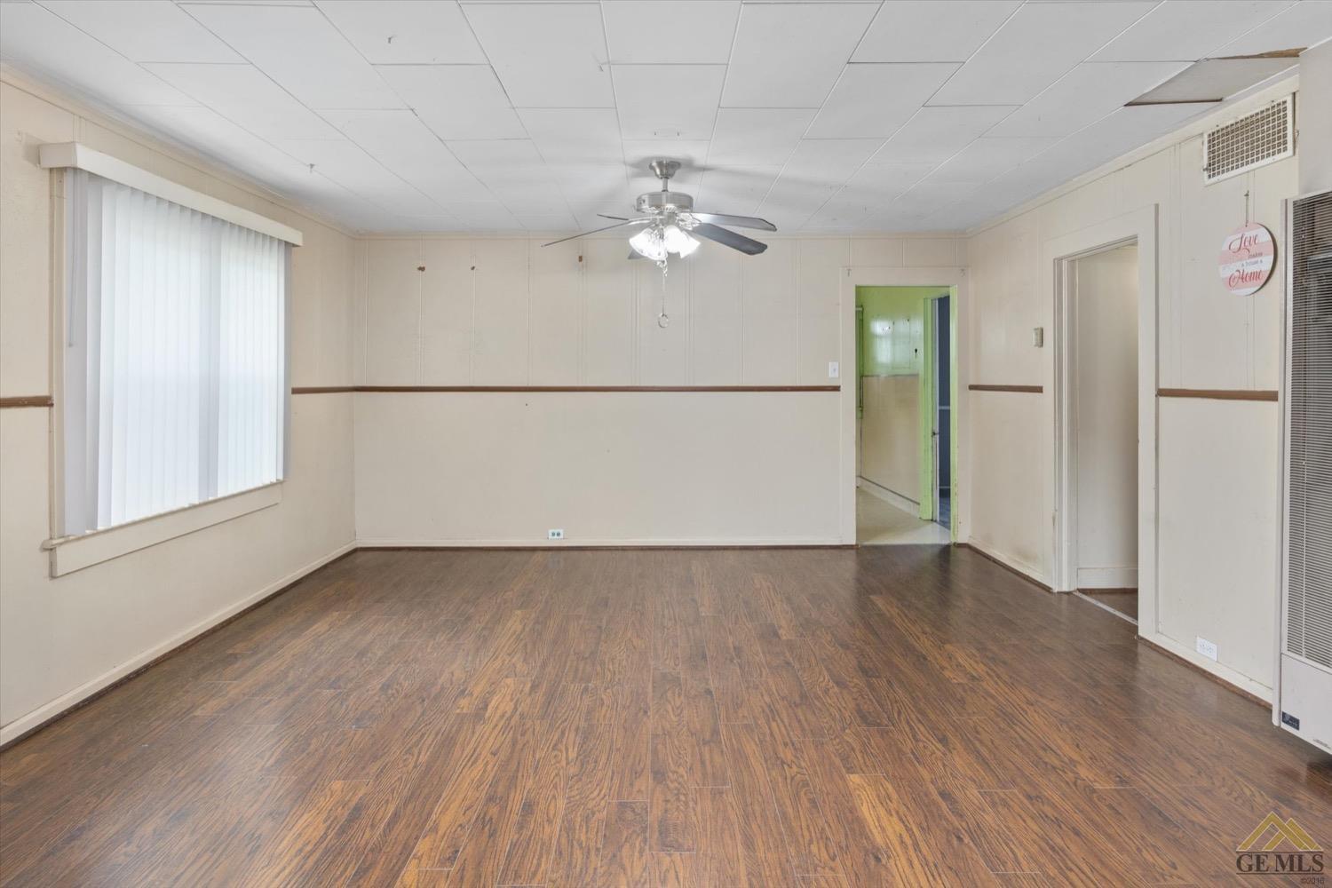 Undisclosed Address Taft, CA 93268 - Photo 12 of 21 an empty room with wooden floor chandelier fan and windows