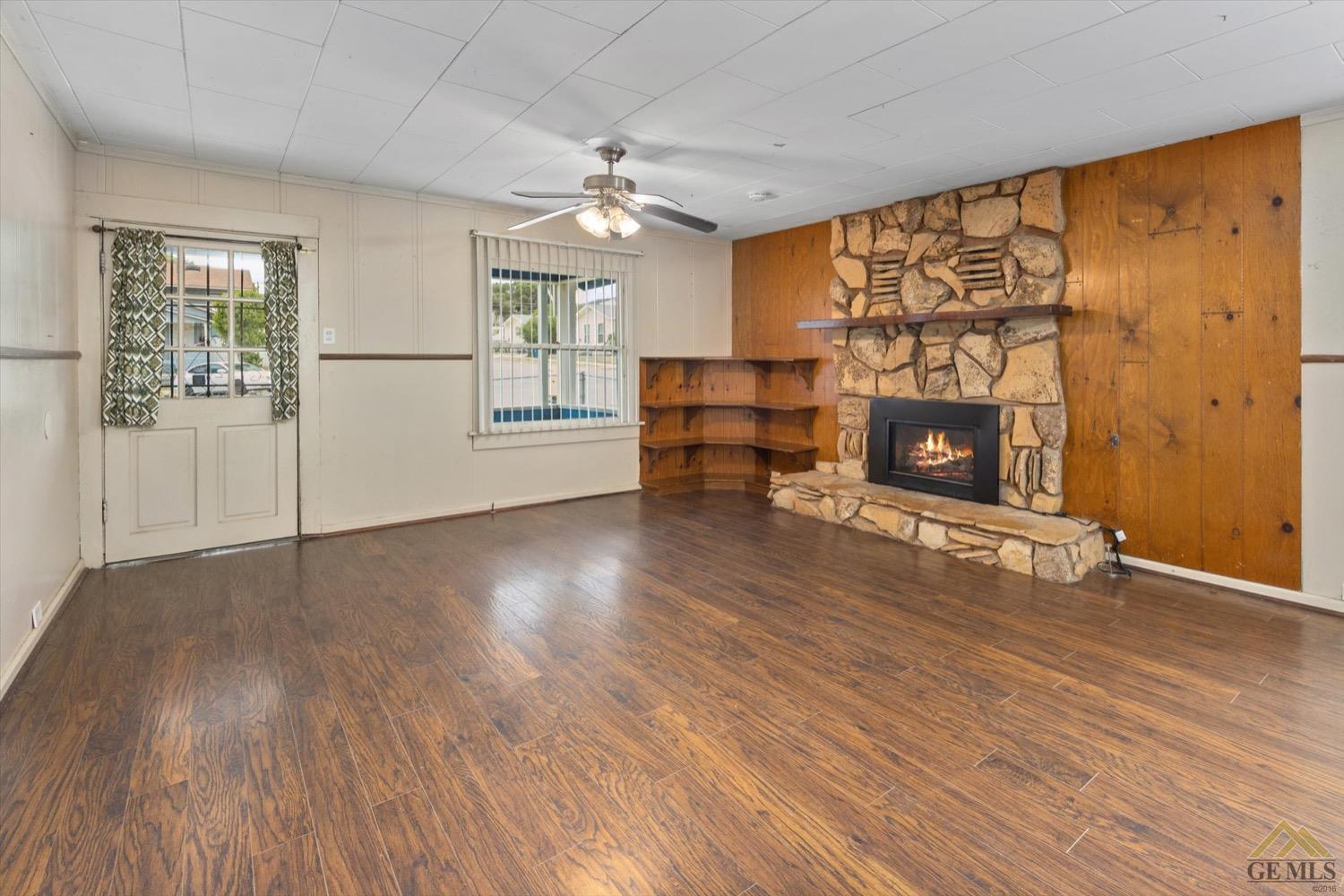 Undisclosed Address Taft, CA 93268 - Photo 5 of 21 an empty room with windows fireplace and wooden floor