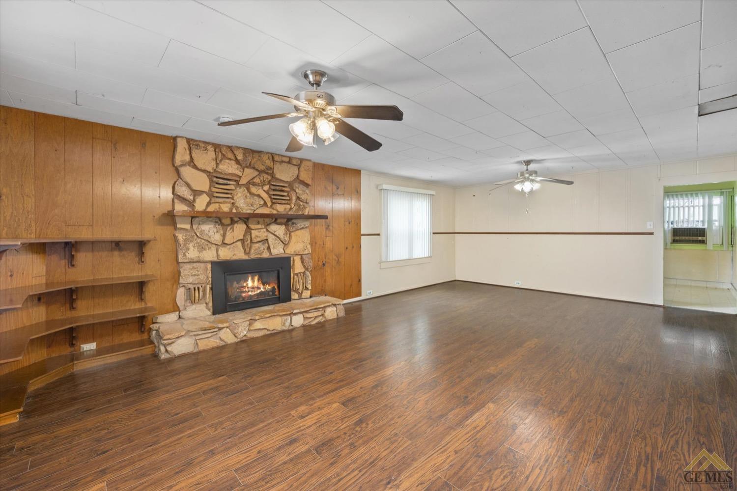 Undisclosed Address Taft, CA 93268 - Photo 8 of 21 an empty room with wooden floor fireplace and windows