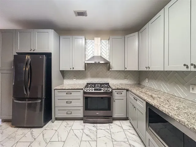a kitchen with stainless steel appliances granite countertop a stove top oven and refrigerator