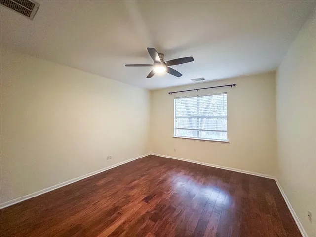 a view of an empty room with window and wooden floor