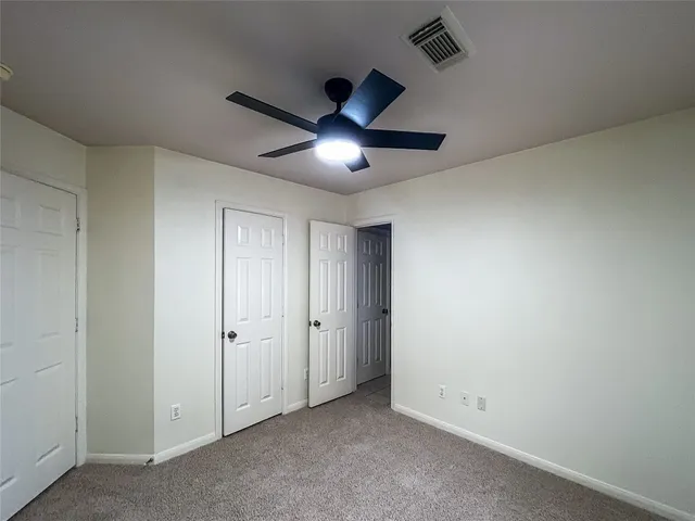 an empty room with chandelier fan and windows