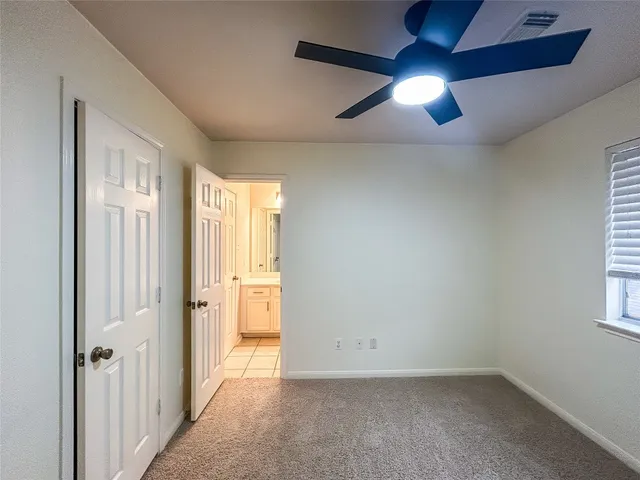 an empty room with chandelier fan and windows