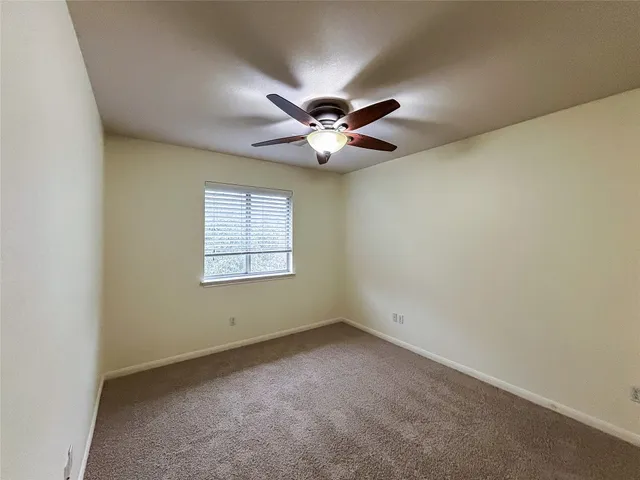 an empty room with windows and ceiling fan
