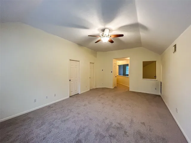 an empty room with chandelier fan and windows