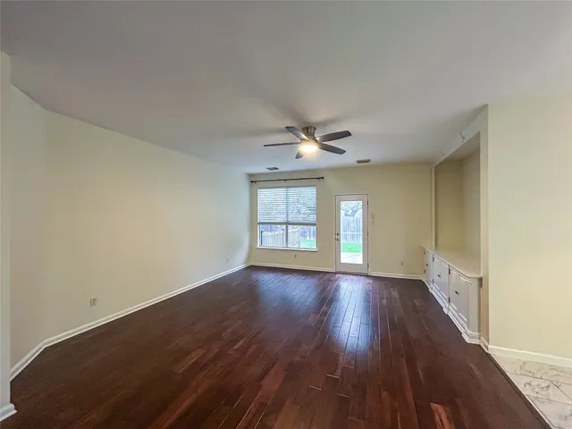 an empty room with wooden floor chandelier and windows