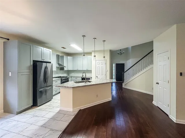 a kitchen with granite countertop a refrigerator and a stove top oven