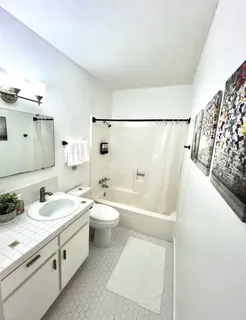 a bathroom with a granite countertop sink a toilet a mirror and shower