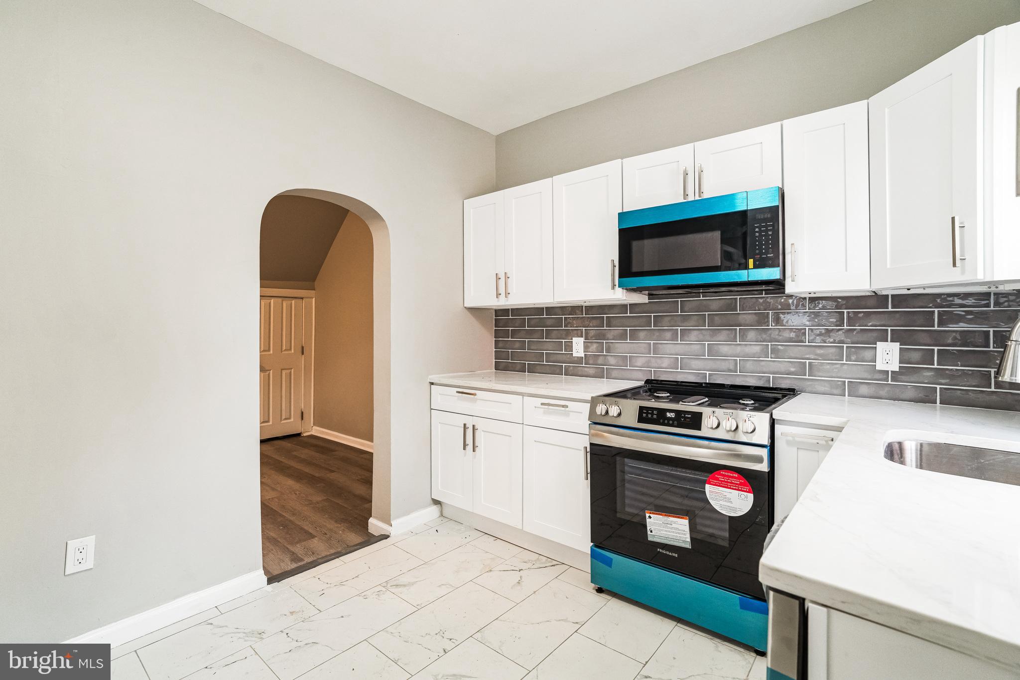 5745 Addison Street Philadelphia, PA 19143 - Photo 12 of 24 a kitchen with granite countertop a stove top oven microwave and cabinets