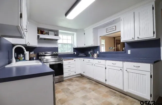 a kitchen with granite countertop white cabinets and stainless steel appliances