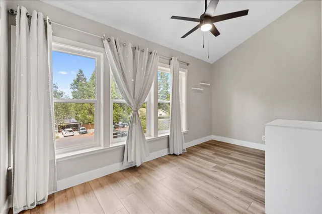 a view of an empty room with a window and hardwood floor