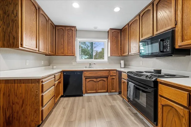 a kitchen with stainless steel appliances granite countertop a stove a sink dishwasher and a microwave oven with wooden cabinets