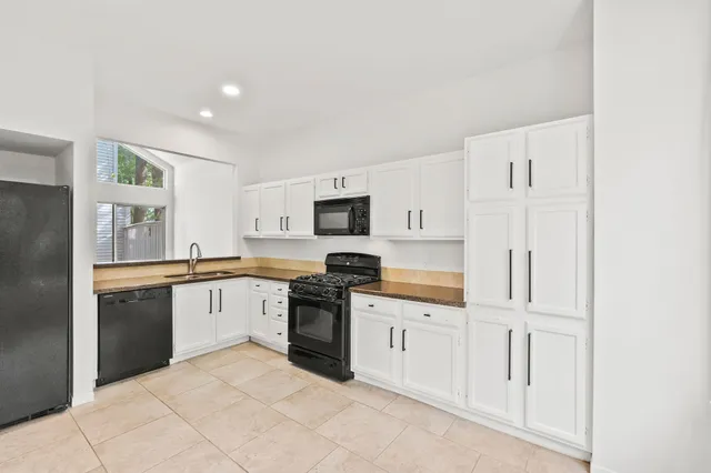a kitchen with granite countertop white cabinets and stainless steel appliances