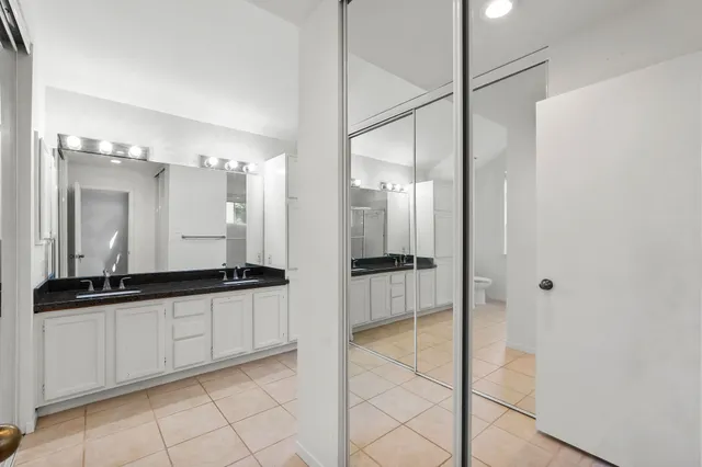 a bathroom with a granite countertop sink a mirror and a shower