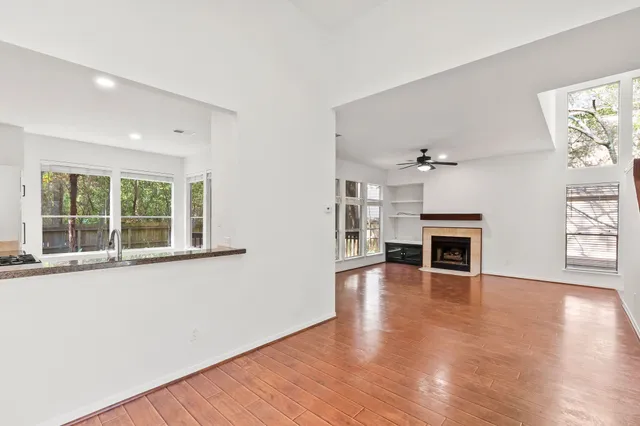 an empty room with wooden floor fireplace and windows