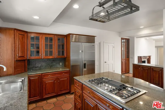 a kitchen with stainless steel appliances granite countertop a stove a refrigerator and a wooden cabinets