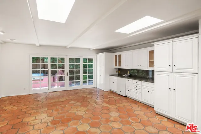 a large white kitchen with granite countertop a stove a sink a window and white cabinets