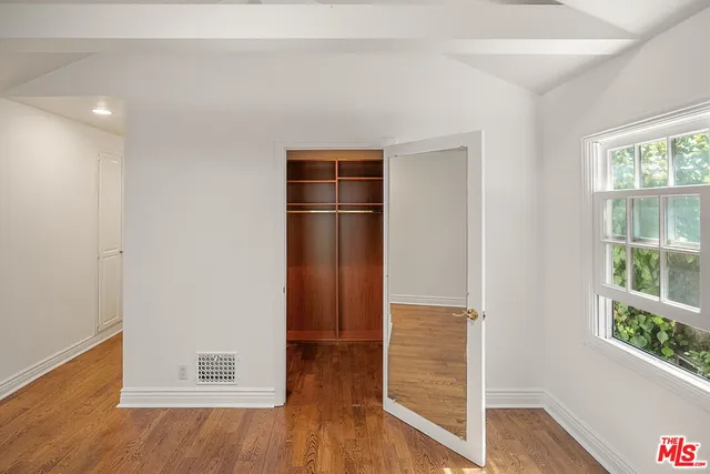 a view of empty room with wooden floor and window