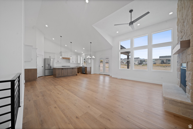 1117 East Shilow Road, Unit 106 Erda, UT 84074 - Photo 3 of 21 Expansive open-concept living space featuring wood-finish flooring, a stone-clad fireplace, and a vaulted ceiling with a modern ceiling fan