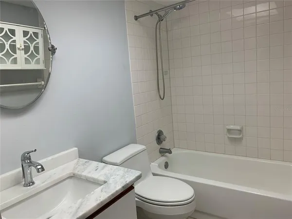a bathroom with a granite countertop bathtub shower sink vanity and toilet