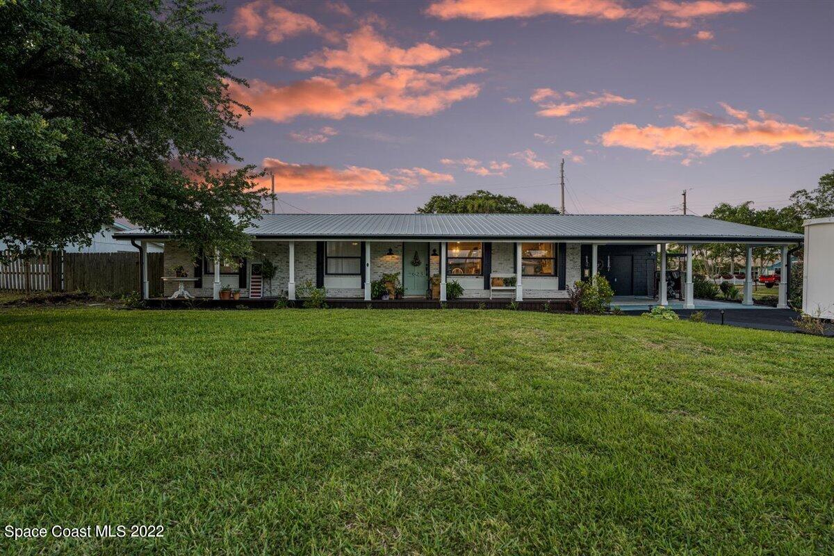 623 Bermuda Road Cocoa Beach, FL 32931 - Photo 3 of 29 a view of a house next to a big yard and large trees