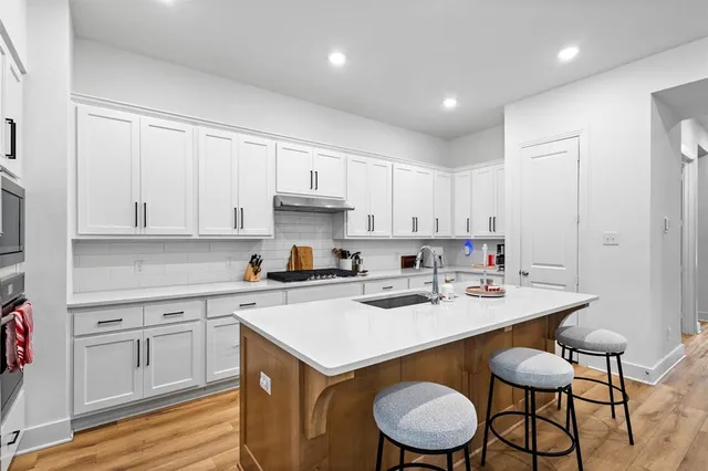 a kitchen with a sink a stove a refrigerator and white cabinets