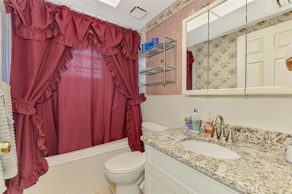 1137 Ponderosa Road Venice, FL 34293 - Photo 31 of 48 a bathroom with a granite countertop sink a toilet and a shower curtain