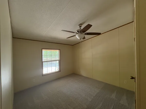 an empty room with a window and a fan