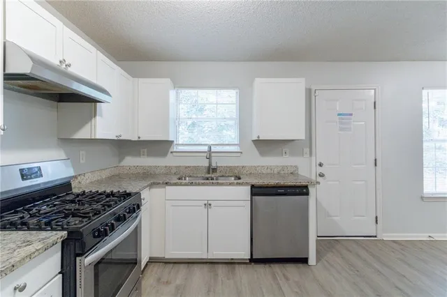 a kitchen with granite countertop stainless steel appliances a sink cabinets and a window