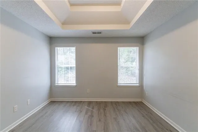 an empty room with wooden floor and windows