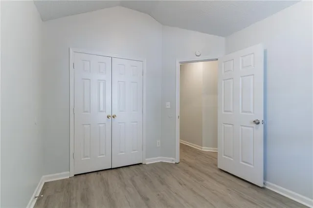 a view of an empty room with closet and wooden floor