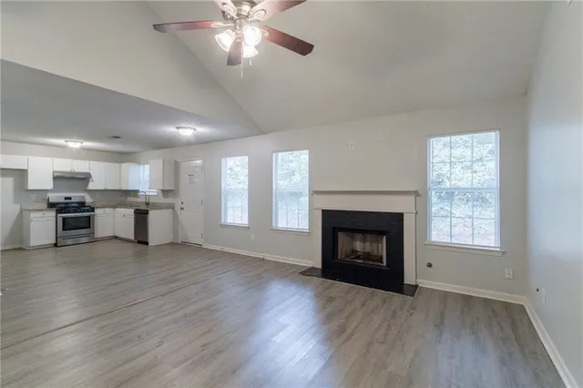 an empty room with wooden floor fireplace and windows