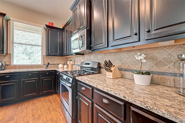 a kitchen with stainless steel appliances granite countertop a stove a sink and a microwave