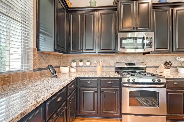 a dining hall with stainless steel appliances granite countertop a dining table and chairs with wooden floor