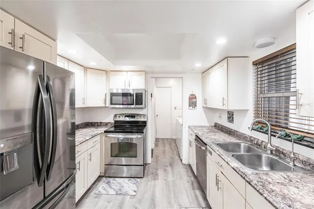 a kitchen with stainless steel appliances granite countertop a stove a sink a refrigerator and cabinets