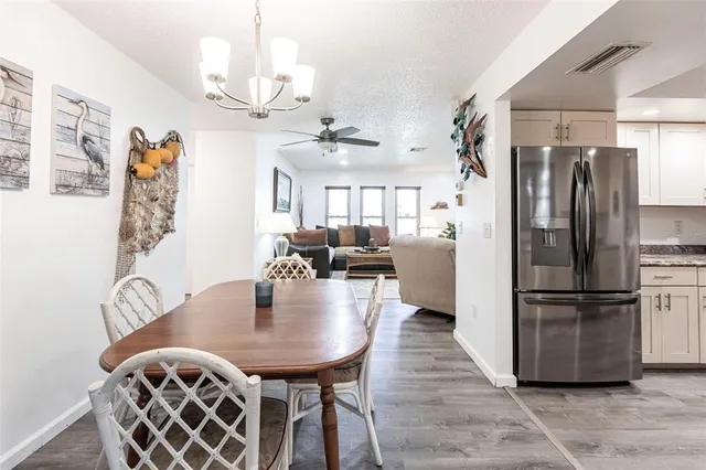 a kitchen with stainless steel appliances granite countertop a dining table chairs a refrigerator and chandelier