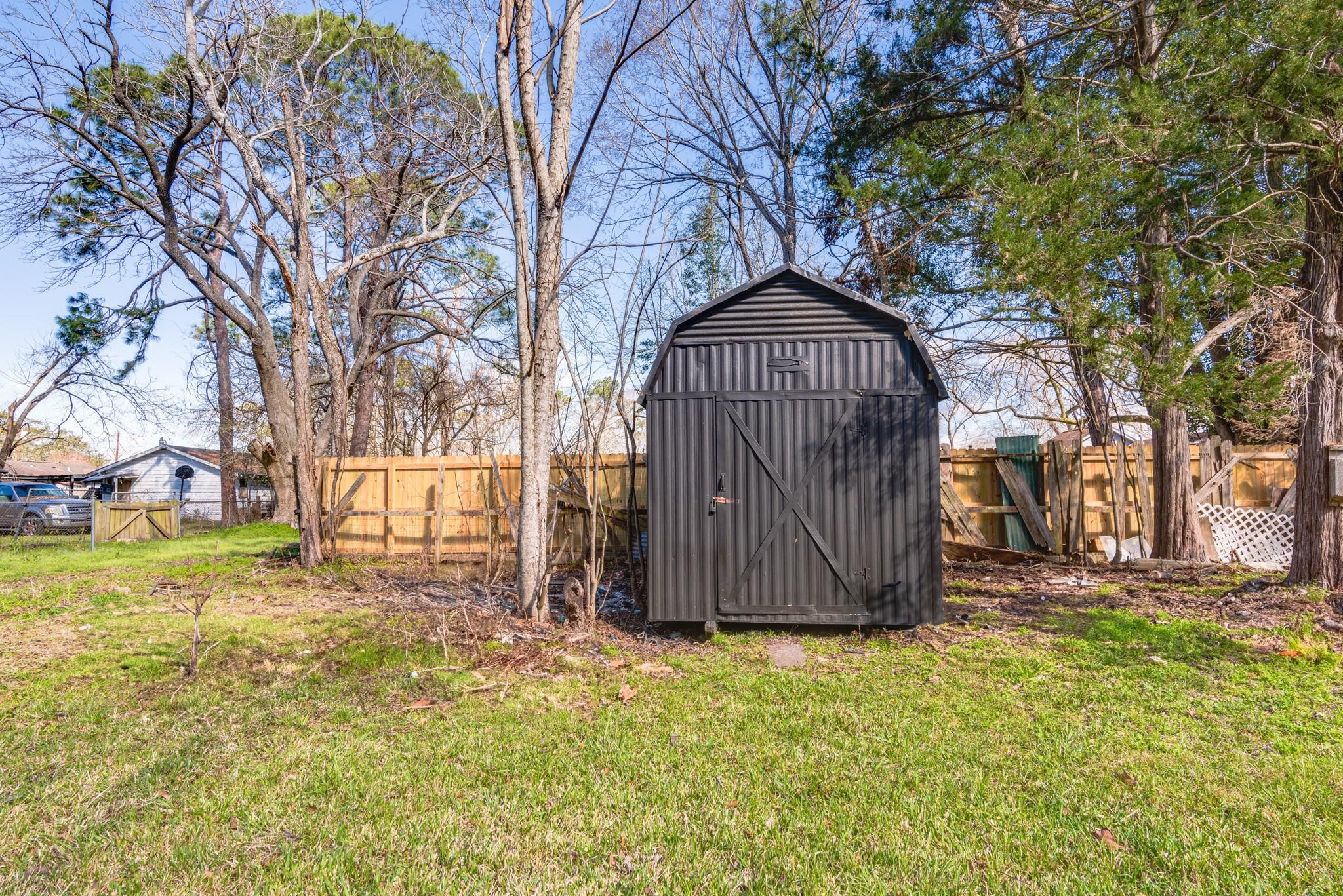 1105 North Valderas Street Angleton, TX 77515 - Photo 16 of 17 a view of a tiny house with a large tree and wooden fence