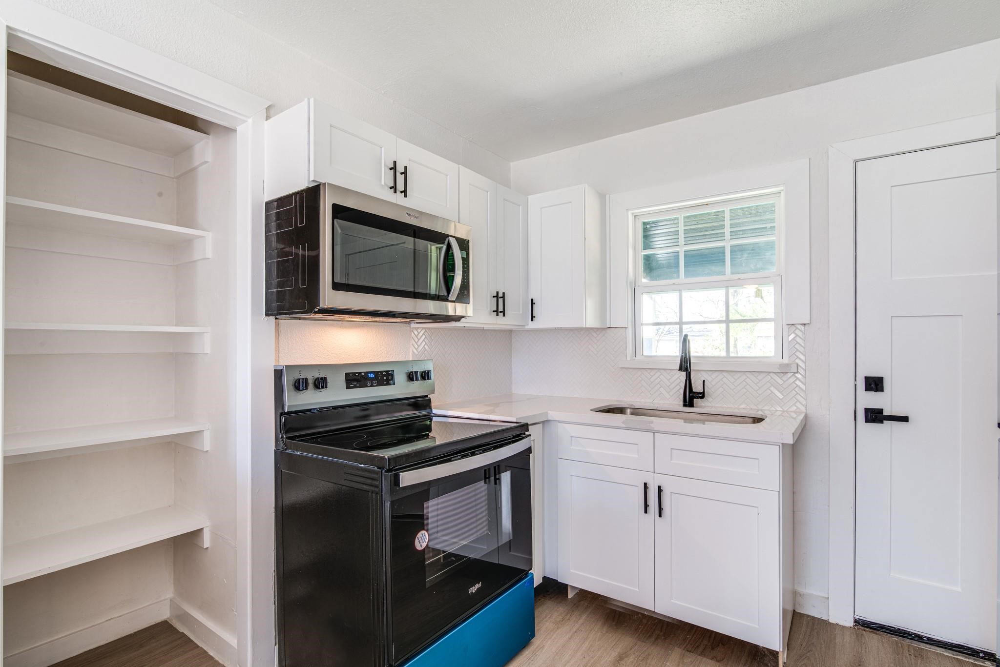 1105 North Valderas Street Angleton, TX 77515 - Photo 4 of 17 a kitchen with a sink stove and microwave