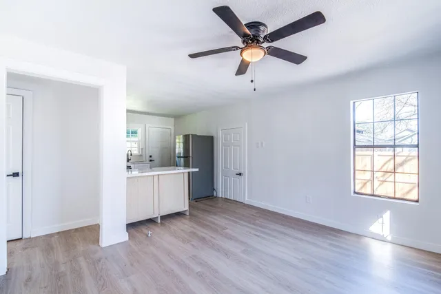 an empty room with windows and chandelier fan