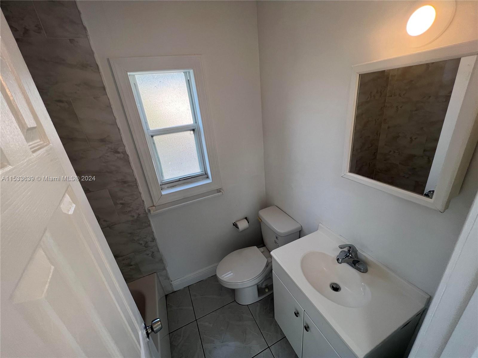 1935 Southwest 2nd Street, Unit 2 Miami, FL 33135 - Photo 5 of 12 a bathroom with a toilet sink and mirror next to a window